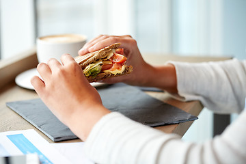 Image showing woman eating salmon panini sandwich at restaurant