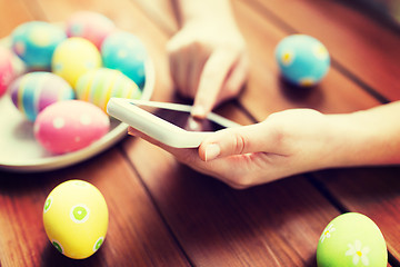 Image showing close up of hands with easter eggs and smartphone