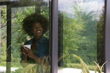 Image showing African American woman drinking coffee looking out the window