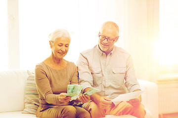 Image showing senior couple with money and calculator at home