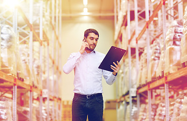 Image showing man with clipboard and smartphone at warehouse