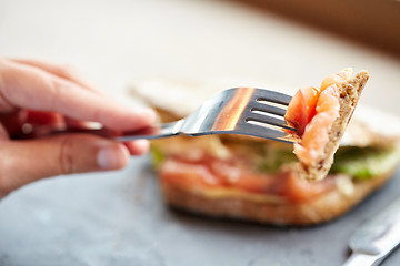 Image showing woman eating salmon panini sandwich at restaurant