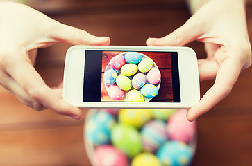 Image showing close up of hands with easter eggs and smartphone