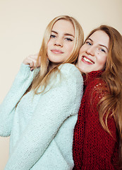 Image showing Two young girlfriends in winter sweaters indoors having fun. Lifestyle. Blond teen friends close up