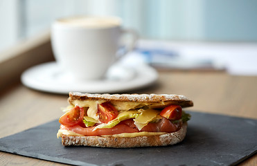 Image showing salmon panini sandwich on stone plate at cafe