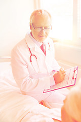 Image showing senior woman and doctor with clipboard at hospital