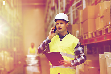 Image showing man with clipboard and smartphone at warehouse