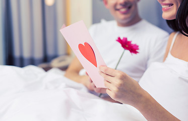 Image showing close up of couple in bed with postcard and flower