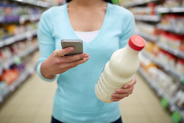 Image showing woman with smartphone buying milk at supermarket