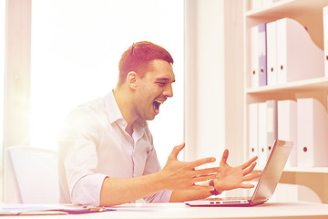 Image showing angry businessman with laptop and papers in office