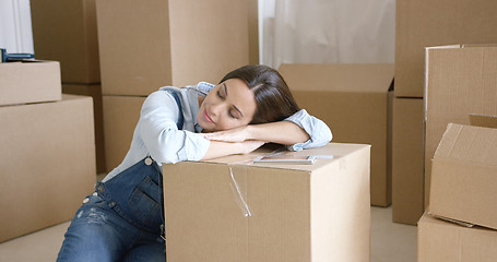 Image showing Young woman taking a nap on a brown carton