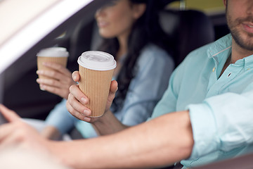 Image showing close up of couple driving in car with coffee cups