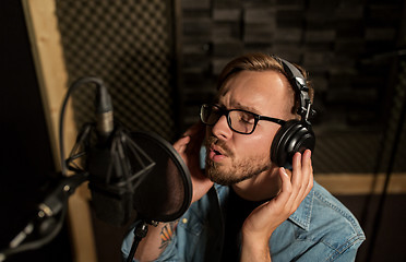 Image showing man with headphones singing at recording studio