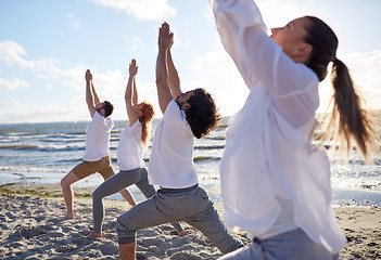 Image showing group of people making yoga exercises on beach