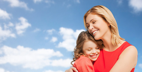 Image showing happy mother and daughter hugging over blue sky