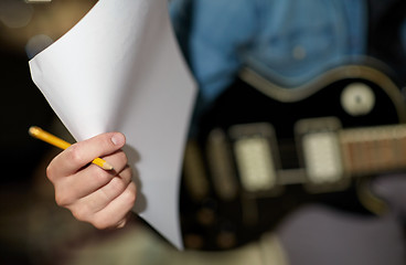 Image showing man with guitar, pencil and paper at music studio