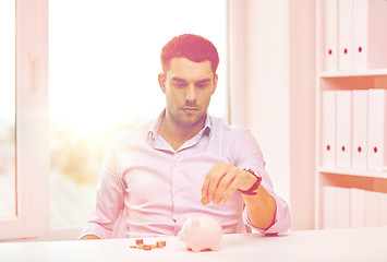 Image showing businessman with piggy bank and coins at office