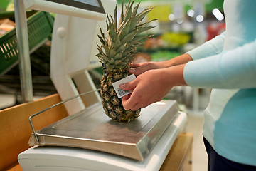 Image showing woman weighing pineapple on scale at grocery store