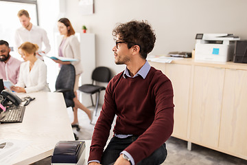 Image showing happy young man over creative team in office