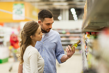 Image showing happy couple buying olive oil at grocery store