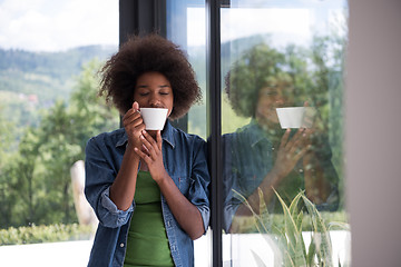 Image showing African American woman drinking coffee looking out the window