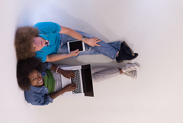 Image showing multiethnic couple sitting on the floor with a laptop and tablet