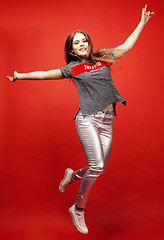 Image showing young pretty emitonal posing teenage girl on bright red background jumping with flying hair, happy smiling lifestyle people concept 