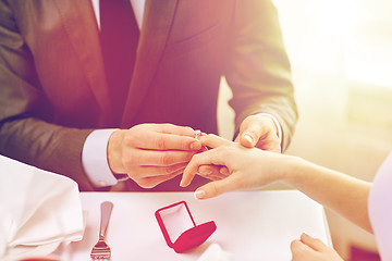 Image showing close up of man putting ring to his fiance finger