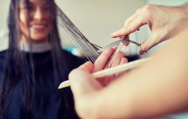 Image showing happy woman with stylist cutting hair at salon