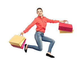 Image showing smiling young woman with shopping bags jumping