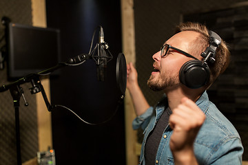 Image showing man with headphones singing at recording studio