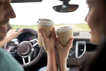 Image showing close up of couple driving in car with coffee cups