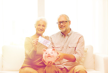 Image showing senior couple with money and piggy bank at home