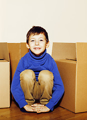 Image showing little cute boy in empty room, remoove to new house. home alone emong boxes close up kid