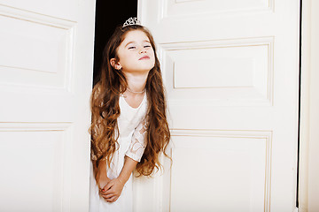 Image showing little cute girl at home, opening door well-dressed in white dre