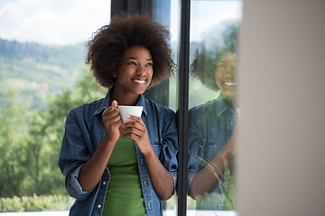 Image showing African American woman drinking coffee looking out the window