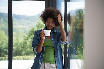 Image showing African American woman drinking coffee looking out the window