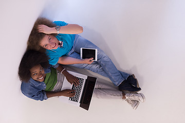 Image showing multiethnic couple sitting on the floor with a laptop and tablet