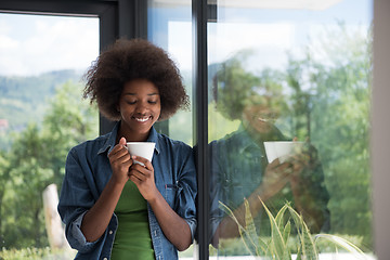 Image showing African American woman drinking coffee looking out the window