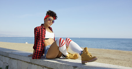 Image showing Trendy young woman relaxing on a beachfront wall