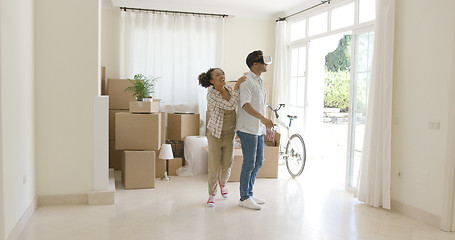 Image showing Young man trying out VR goggles guided by his wife