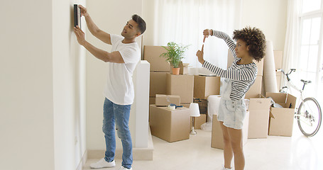 Image showing Young couple hanging pictures in their new home