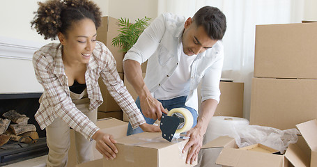 Image showing Couple taping boxes as they pack up their home