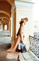 Image showing young pretty smiling woman in hat with bags on shopping at store