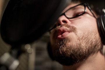 Image showing man with headphones singing at recording studio