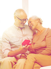 Image showing happy senior couple with red gift box at home