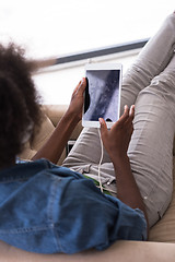 Image showing African american woman at home in chair with tablet and head pho