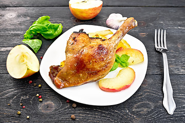 Image showing Duck leg with apple and basil on black board