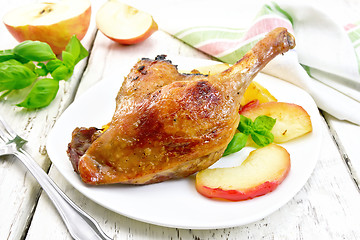 Image showing Duck leg with apple in plate and napkin on board