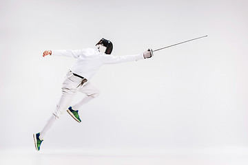 Image showing Man wearing fencing suit practicing with sword against gray